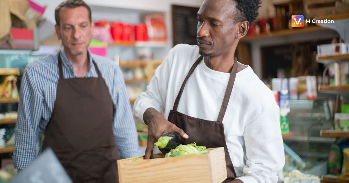 Men working in a grocery store arranging fresh vegetables and fruits. Indoor setting, focused on organic produce.