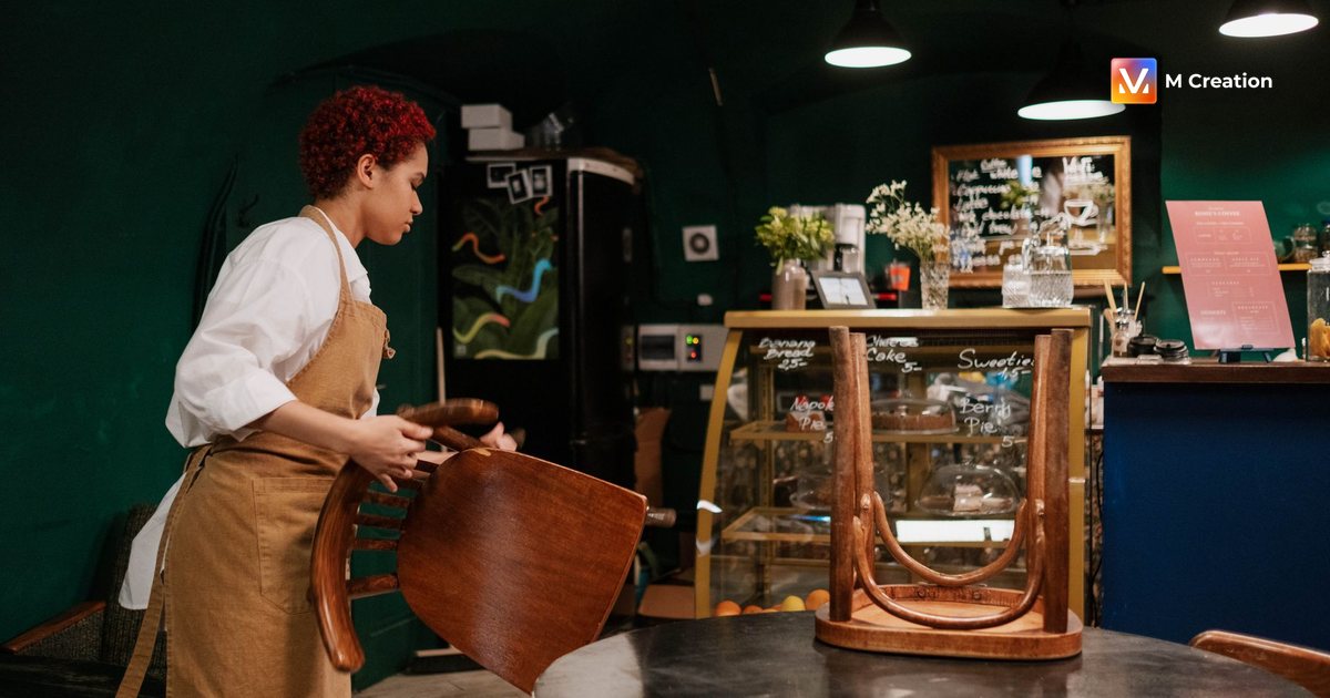 Female waitress cleaning and organizing a cozy café with wooden interior and ambient lighting.